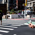 A woman uses a new 24th Street crosswalk to cross Broadway. Department of Transportation officials installed the new walkway after closely studying the intersection and finding that thousands of pedestrians each day would venture into traffic and cross at the intersection, despite the previous lack of a signal and crosswalk.</br>